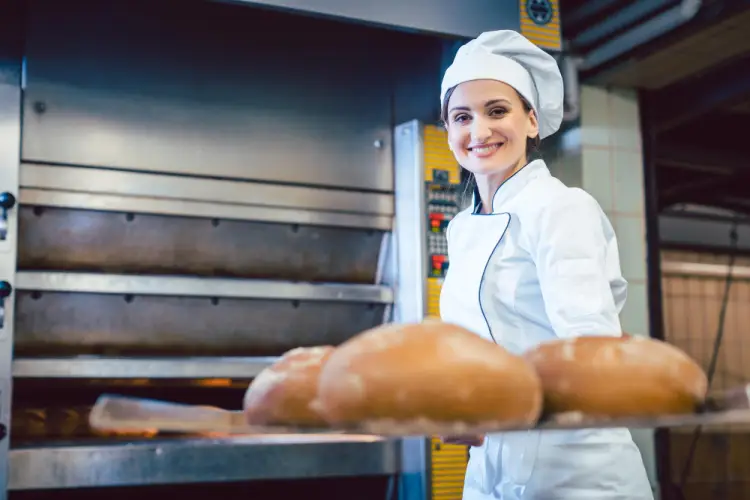 happy-female-baker-with-loaves-of-bread-in-oven.jpg