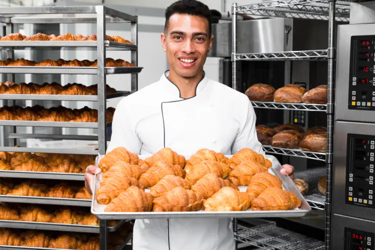 smiling-baker-holding-tray-of-croissants.jpg