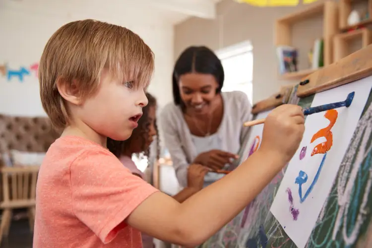 child-painting-with-caregiver-in-preschool.jpg