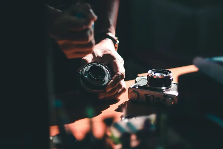 man-cleaning-lens-on-desk.jpg