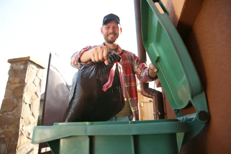 man-placing-garbage-bag-in-outdoor-bin.jpg