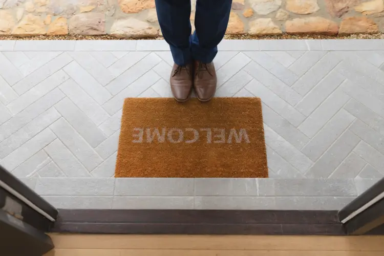 man-standing-near-welcome-mat-front-door-home.jpg